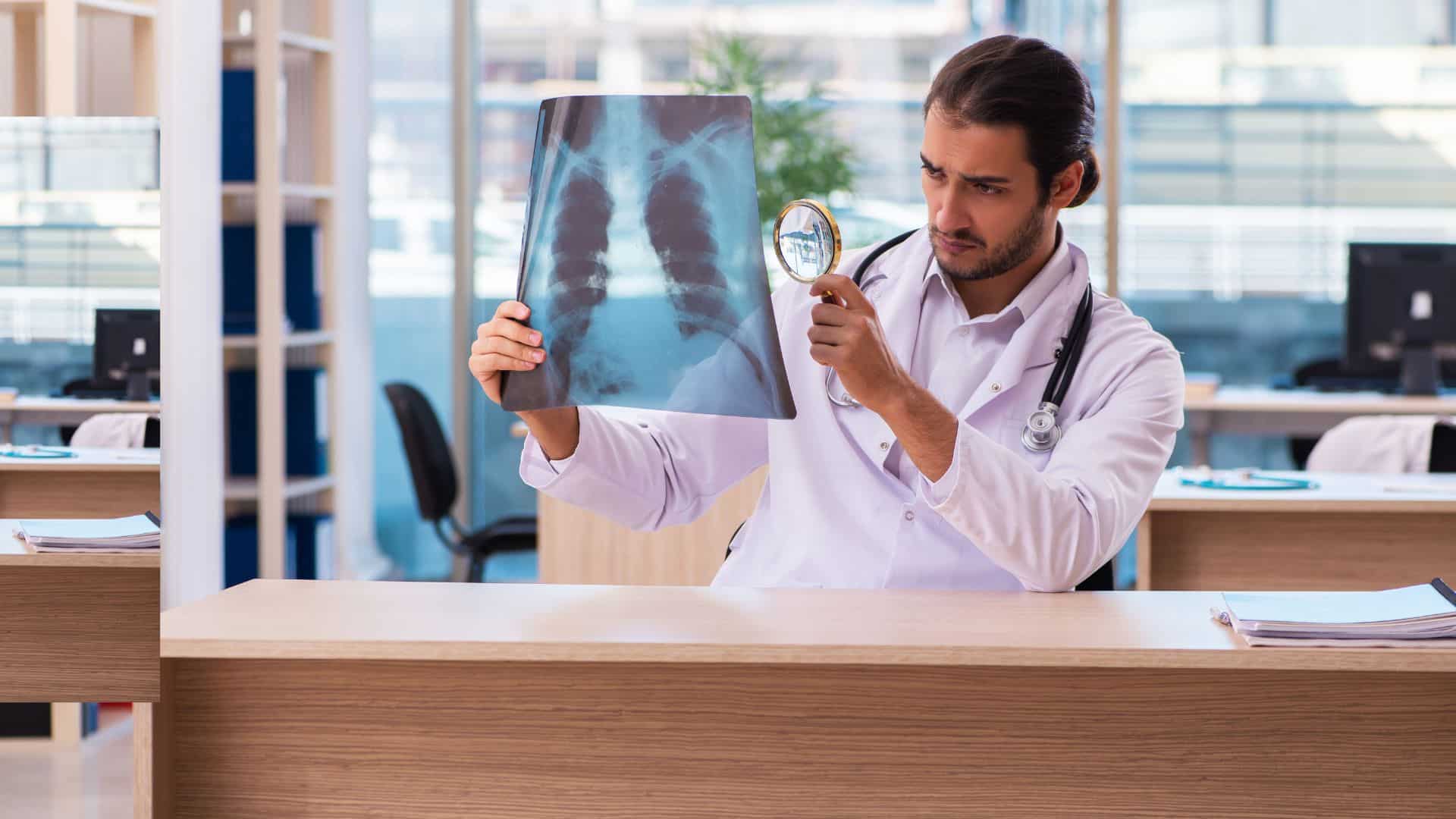Arzt schaut mit Lupe auf Röntgenbild